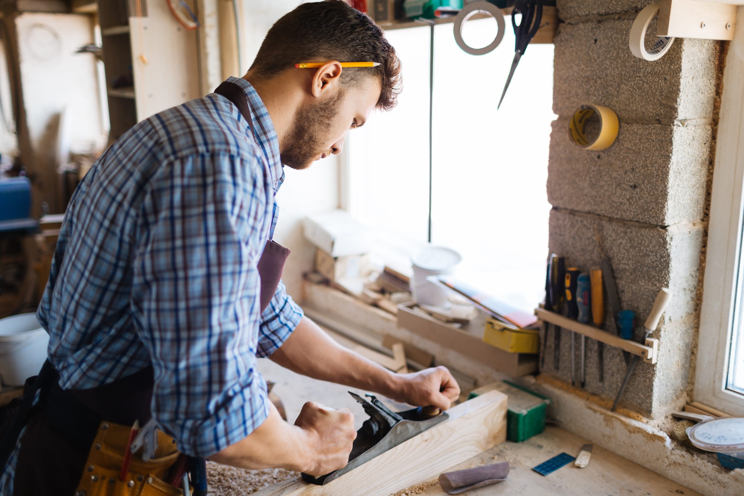 focused-man-works-wood-with-hand-plane