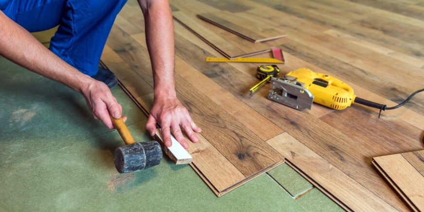 man-installing-wood-flooring-with-tools