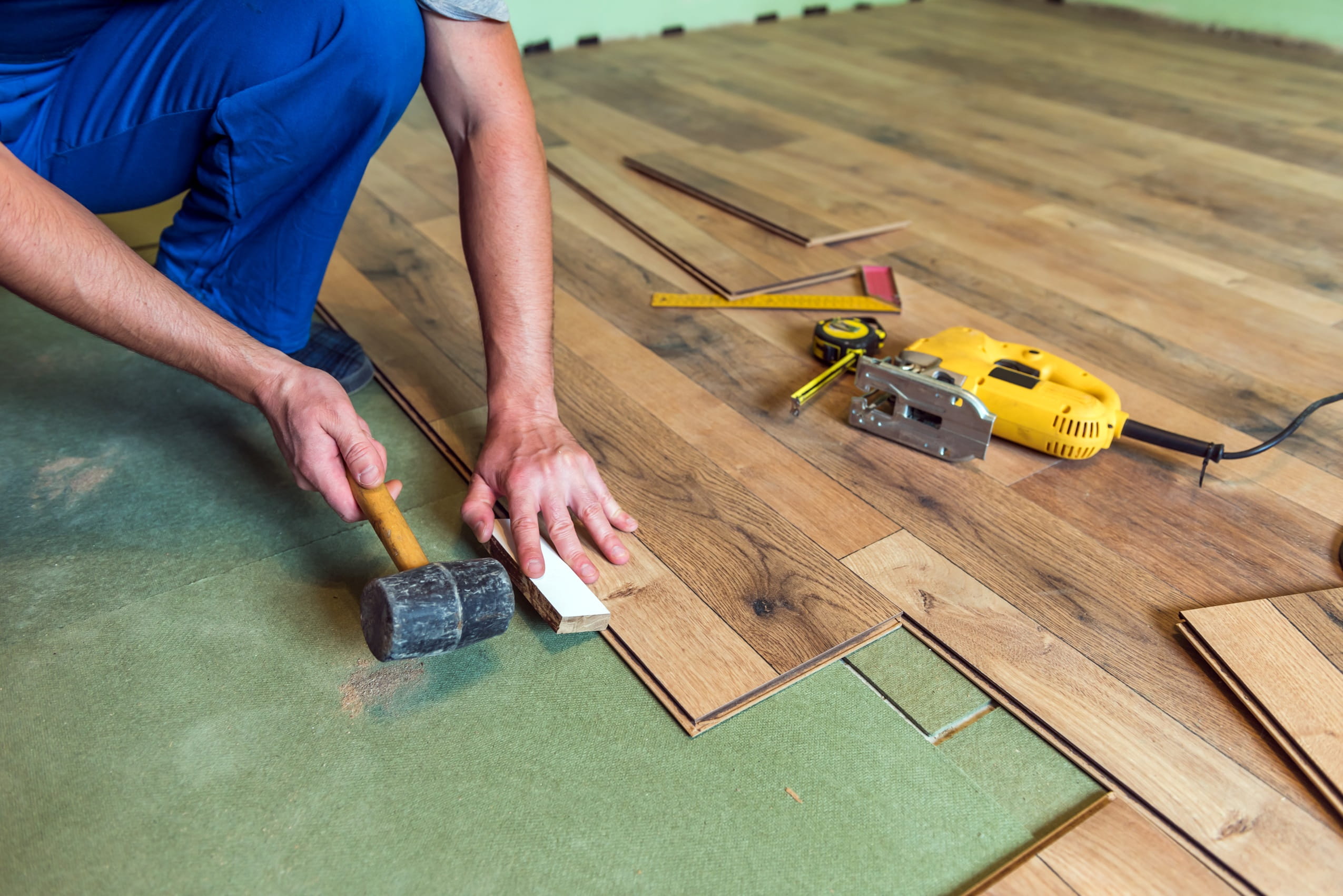man-installing-wood-flooring-with-tools