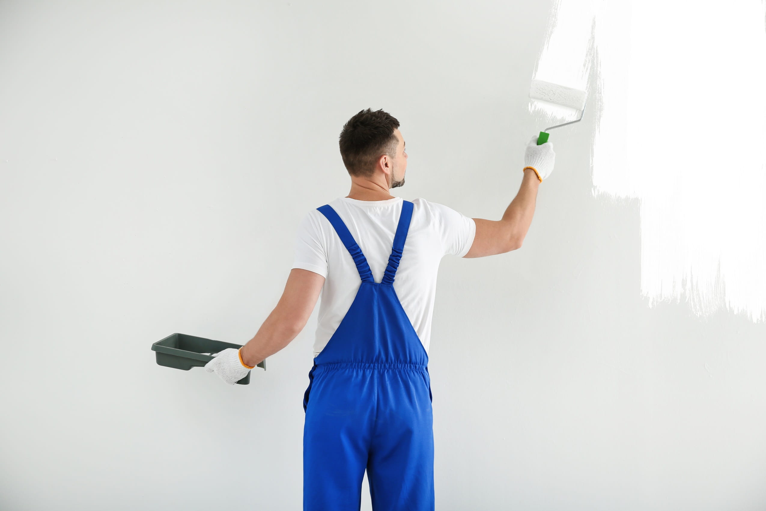 man-painting-wall-with-white-dye-indoors