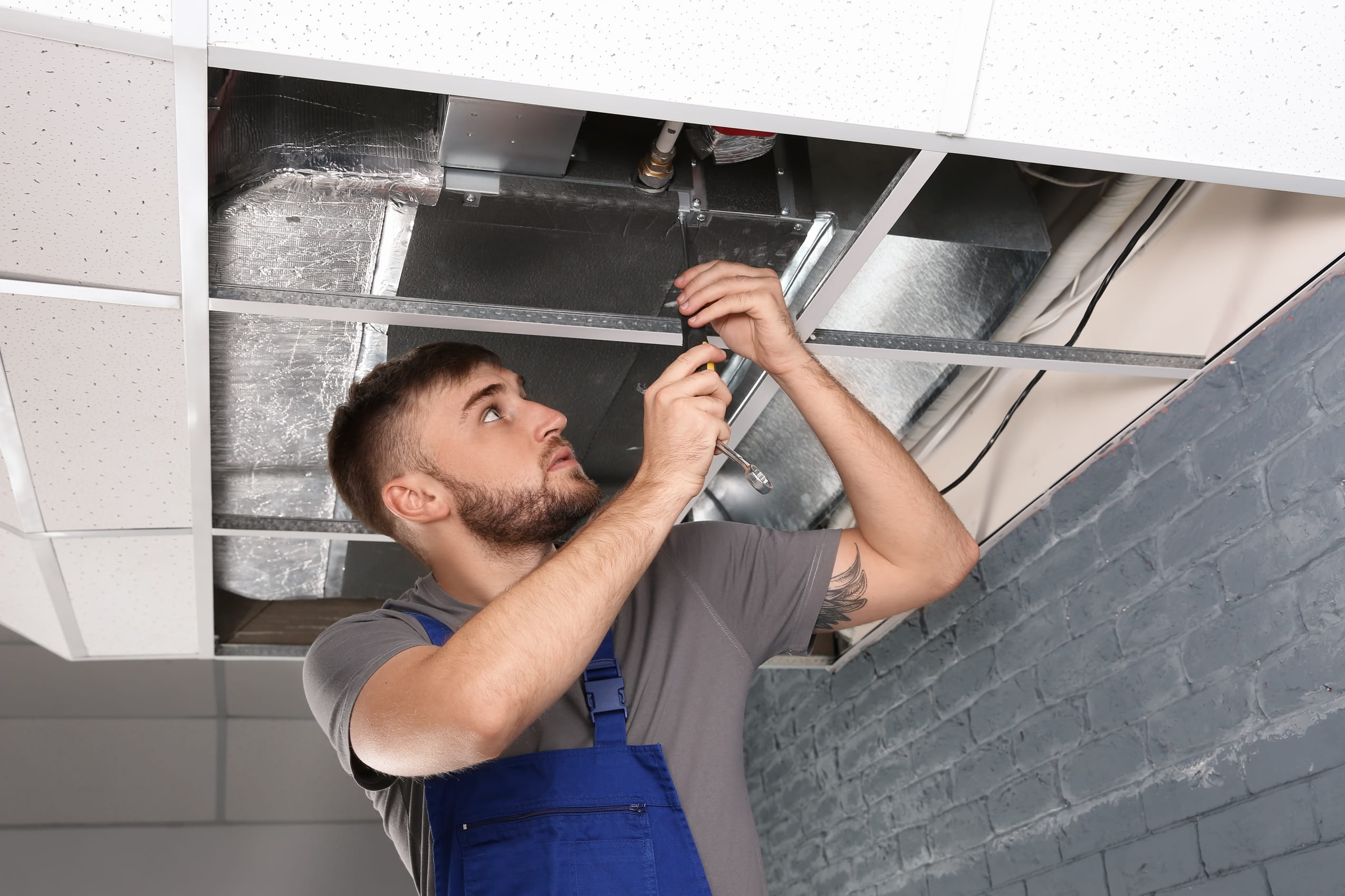 man-repairs-air-conditioning-system-in-building