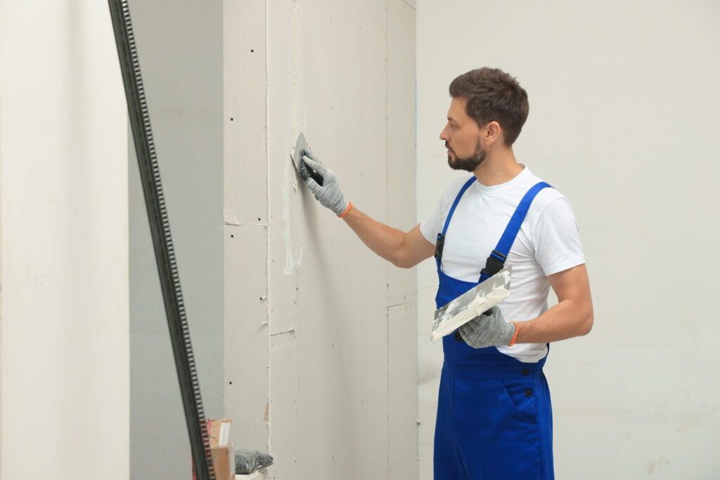 man-smoothing-plaster-on-wall-construction-indoors