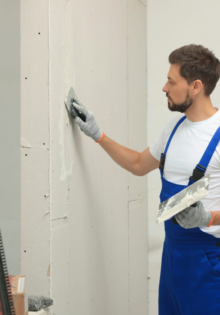 man-smoothing-plaster-on-wall-construction-indoors