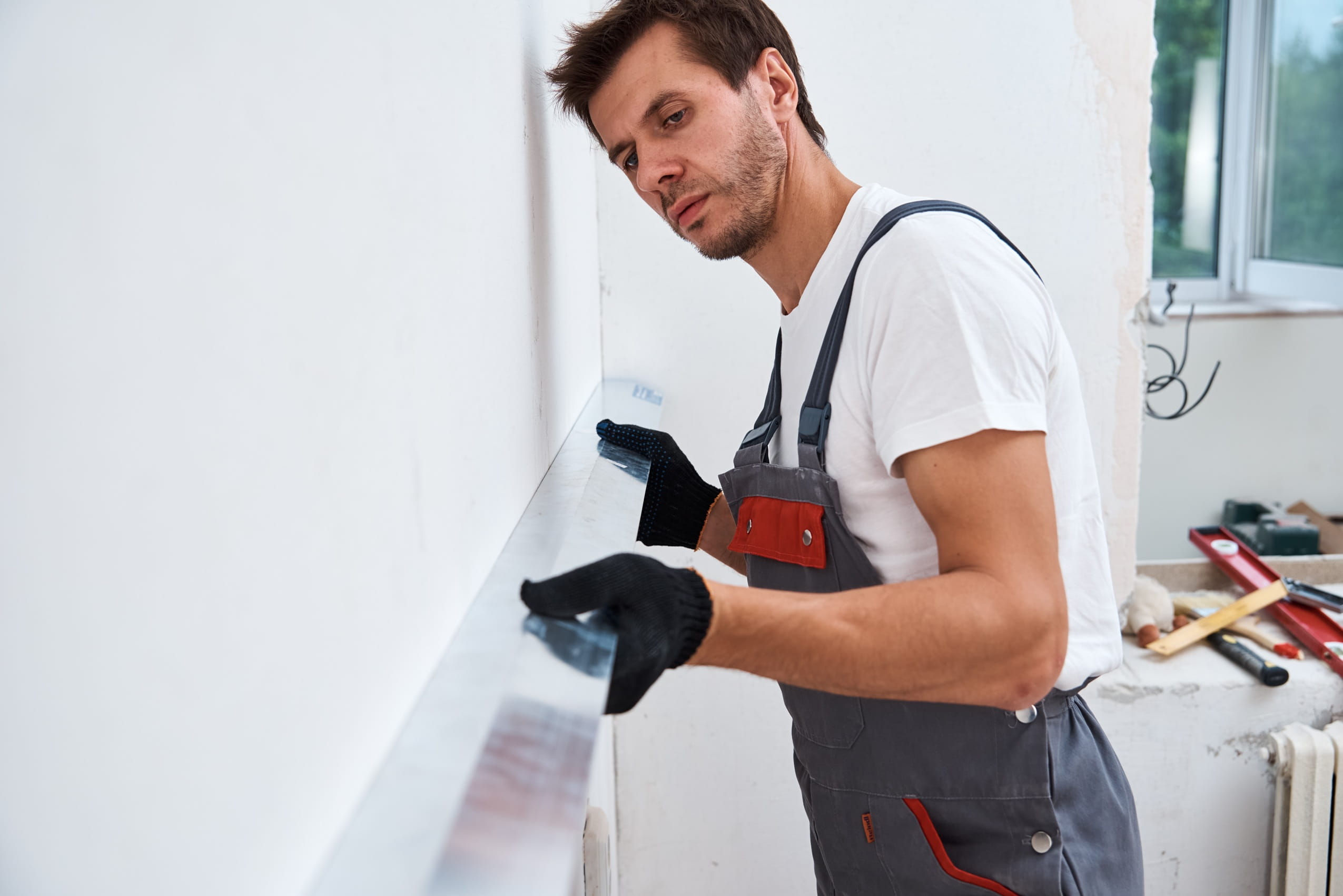 man-working-on-wall-repair-with-level